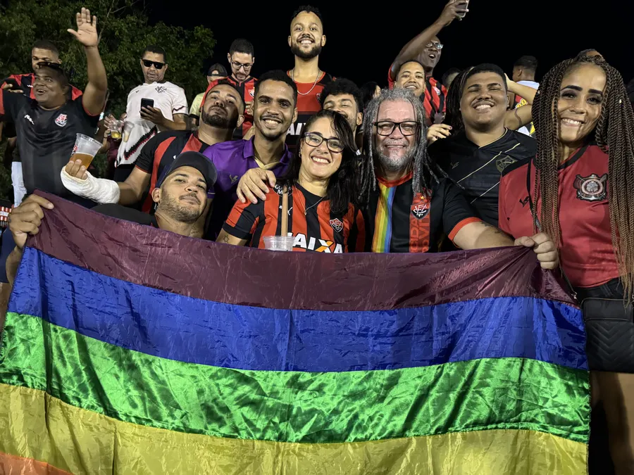 Integrantes da ORN abrindo a bandeira arco-íris na arquibancada à noite